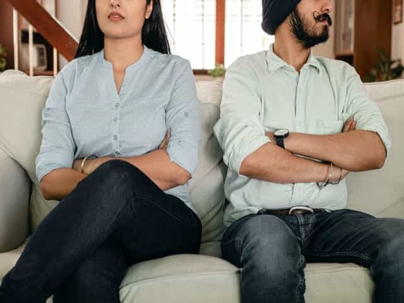 Two people sitting on a couch with their arms crossed.